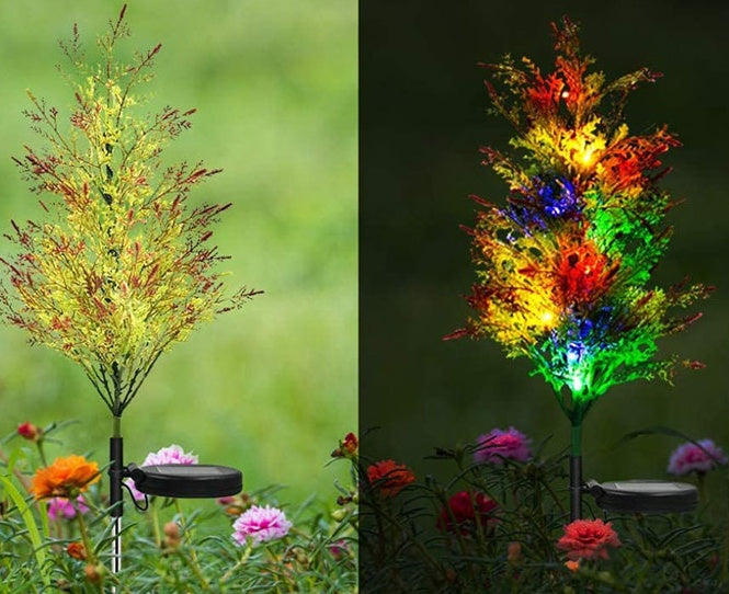Solar-powered LED Christmas lights on decorative pine and cypress trees in garden.