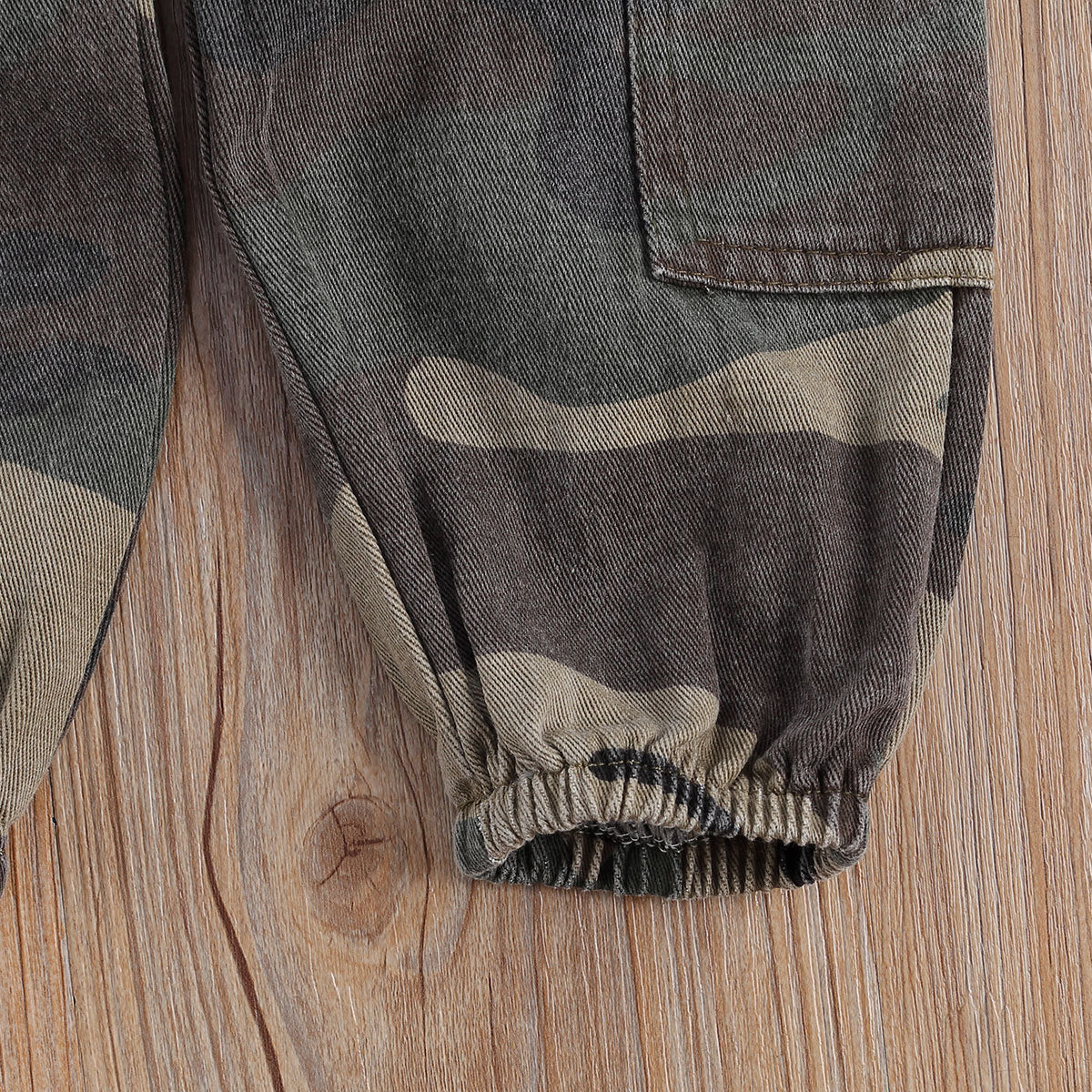 Close-up of black camouflage print trousers for girls, showcasing elastic ribbing and detailed pattern.