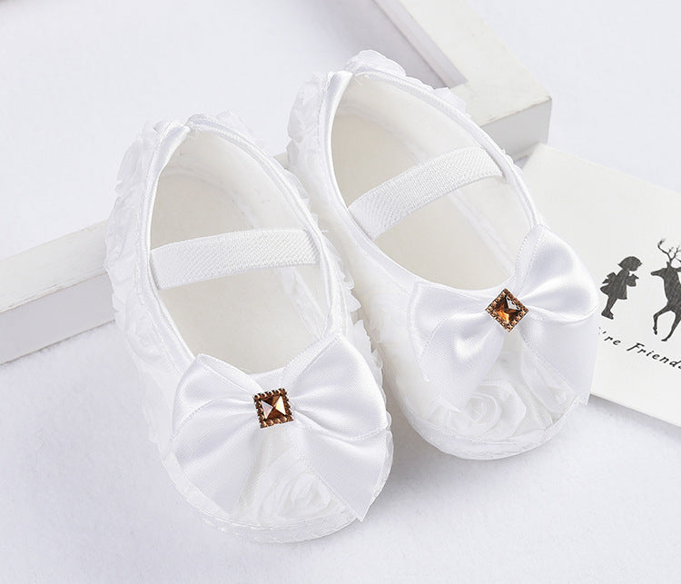 Newborn toddler shoes with silk upper, princess style, anti-slip sole, white with bow embellishment.