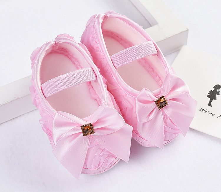 Pink baby-girl toddler sneakers with soft sole, silk upper, and bow detail.