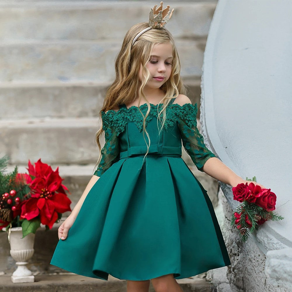 Girl wearing a deep green lace dress with floral accents, standing on steps.