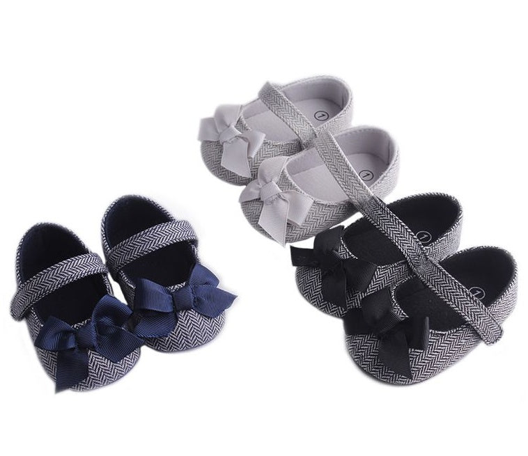 Toddler crib shoes for baby boy in navy and white with bows.