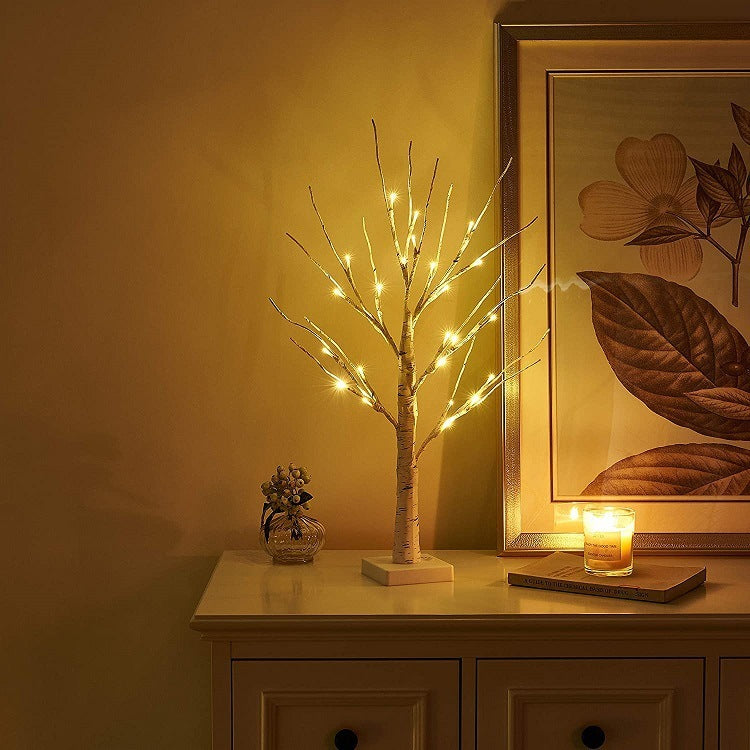 Warm light Christmas decoration lights on a birch tree, displayed on a living room shelf.