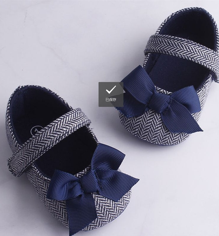 Toddler crib shoes with herringbone design and navy bows.