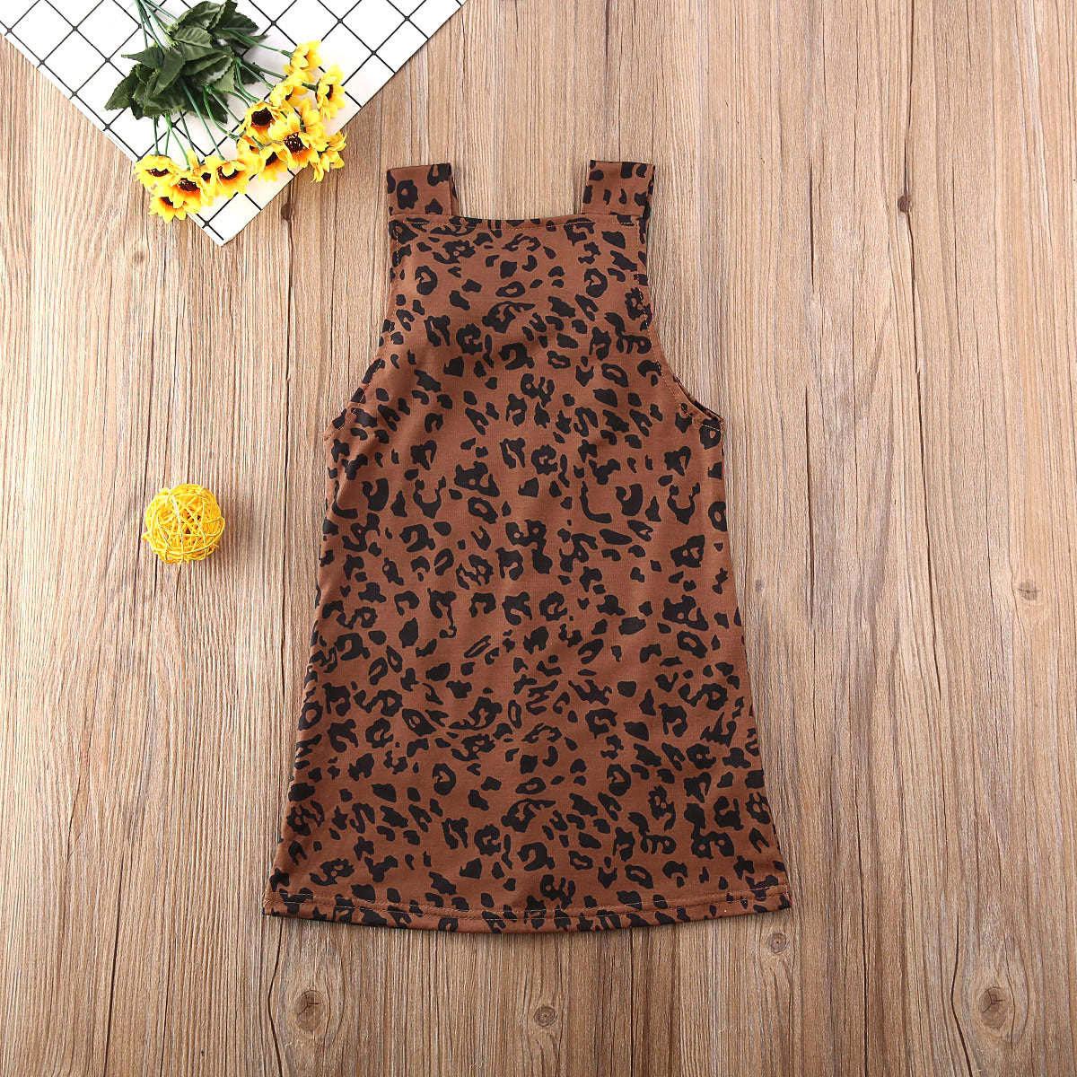 Baby girls' sleeveless leopard print dress on wooden background.