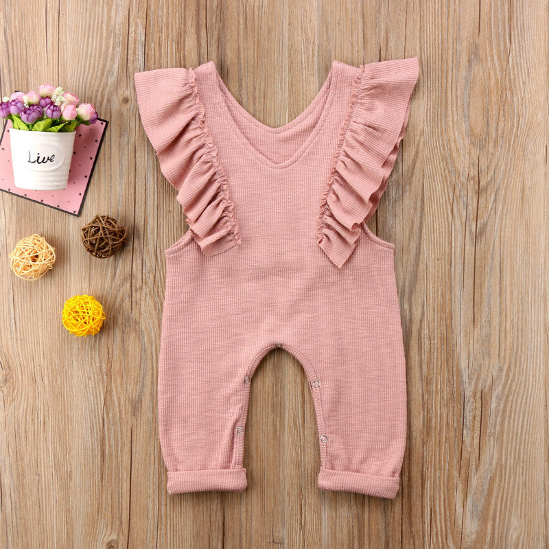 Baby girl pink knitted ruffle jumpsuit, long sleeve romper outfit on wooden background.
