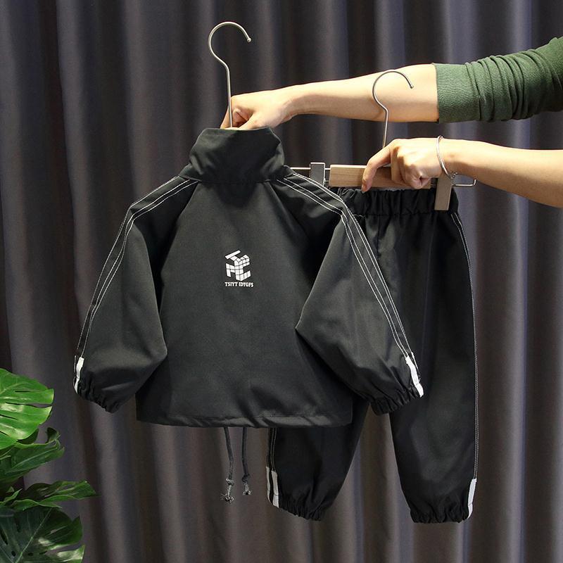 Stylish black two-piece suit for kids, cotton material with white accents, hanging on a hanger.
