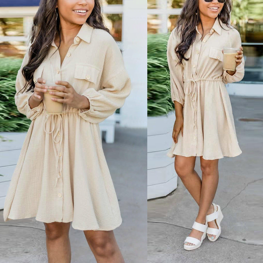 Casual beige button-down dress with drawstring waist, long sleeves, and collar, modeled outdoors.
