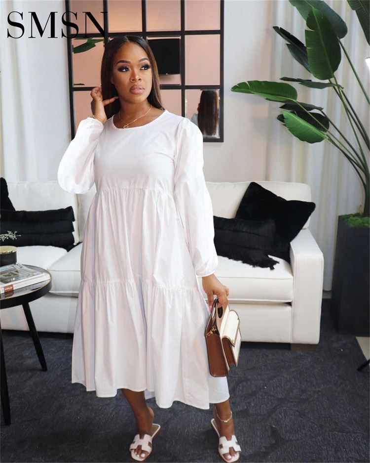 Trendy plus size women’s long sleeve casual dress in white, shown in a stylish living room setting.