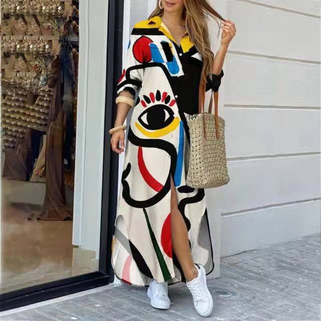 Fashionable woman wearing a long, printed shirt dress with bold colors standing outside a shop.