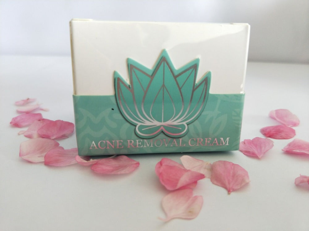 Acne removal cream box surrounded by pink petals.