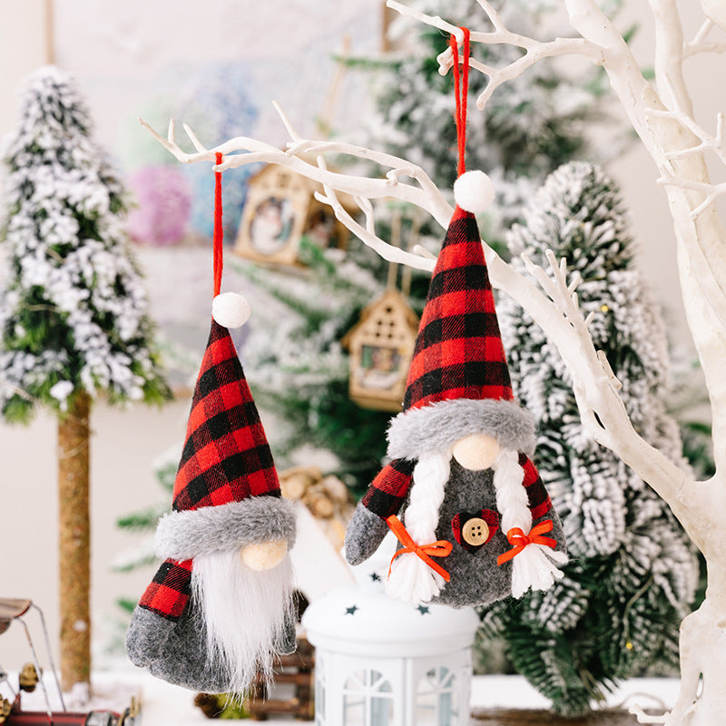 Faceless Christmas gnome dolls in red and black plaid with lights, hanging on a tree branch.