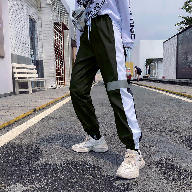 Mens Reflective Track Pants in Black on a model outdoors, showing light side panels and reflective detailing