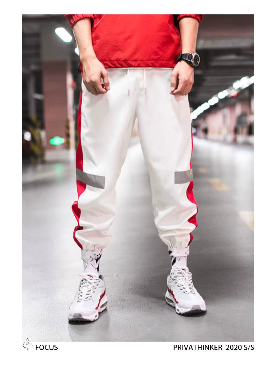 Mens Reflective Track Pants in White on a model, front view showing red side panels, reflective bands and gathered ankles