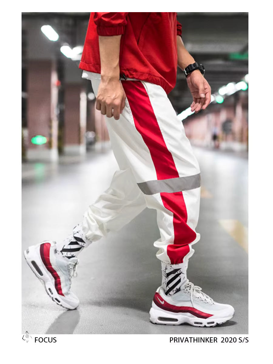 Mens Reflective Track Pants in White on a model, showing red side panels, reflective bands and gathered ankles