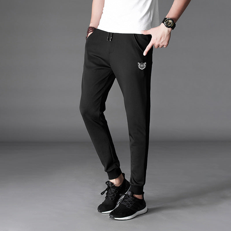 Mens Slim Fit Harem Pants in Black on a model wearing a white T-shirt, showing the tapered legs and small printed detail