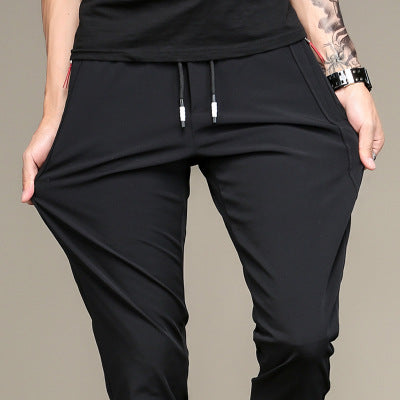 Mens Thick Stretch Trousers in Black on a model pulling the fabric outward, showing the drawstring waist and slim fit
