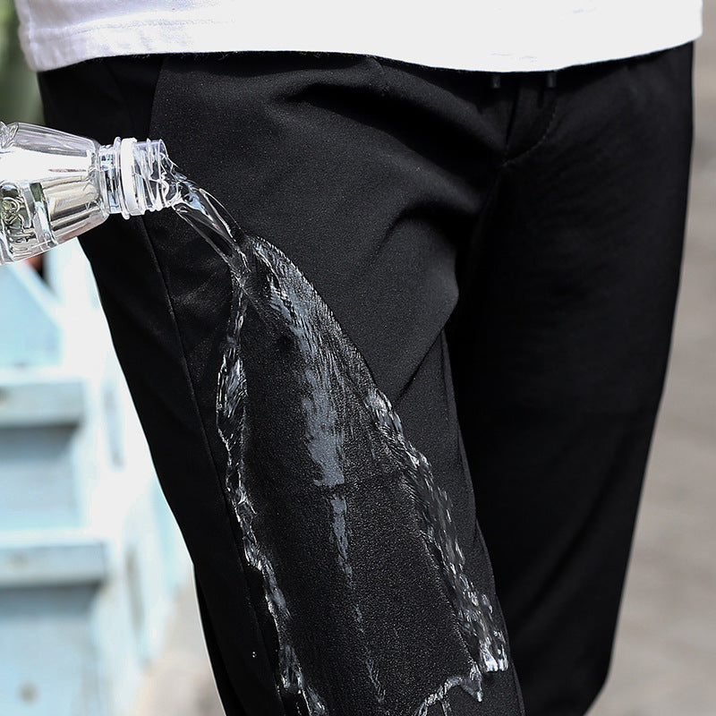 Mens Thick Stretch Trousers in Black, close-up showing water being poured onto the thigh fabric