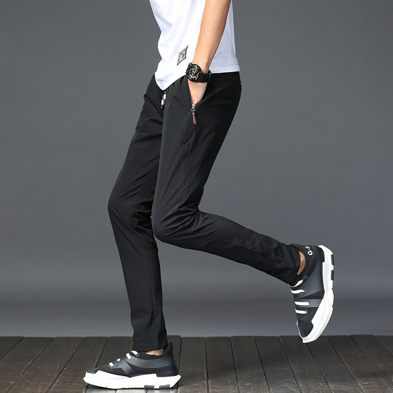 Mens Thick Stretch Trousers in Black on a model, side view with one leg bent and black trainers
