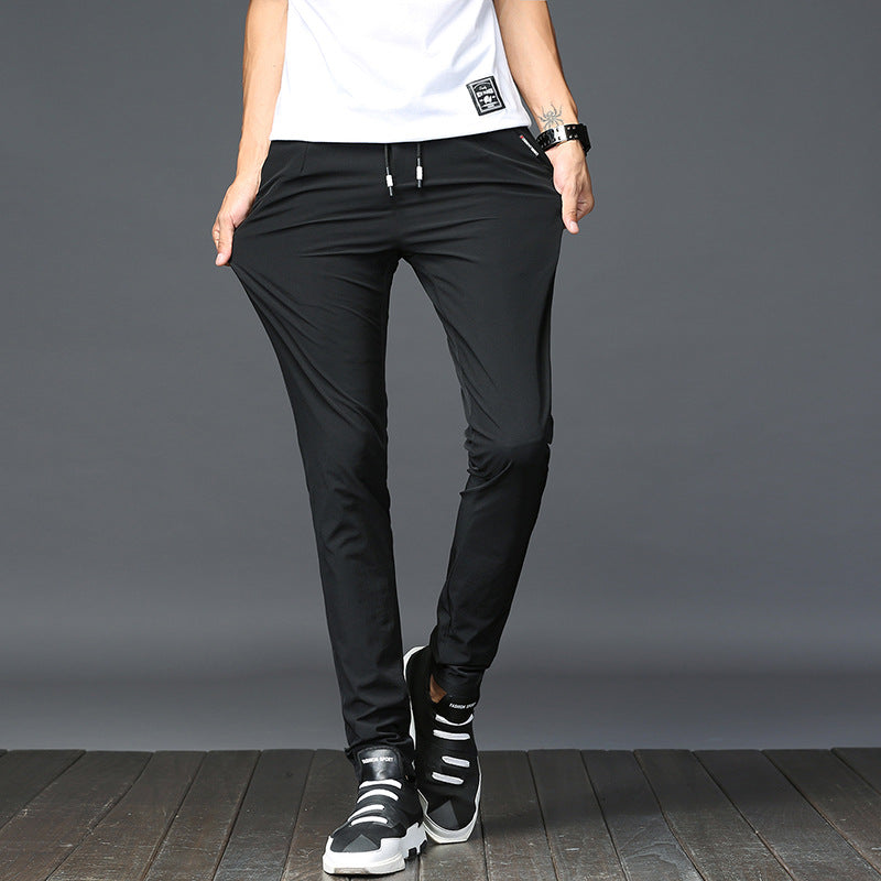 Mens Thick Stretch Trousers in Black on a model wearing a white T-shirt, front view showing the drawstring waist and tapered fit