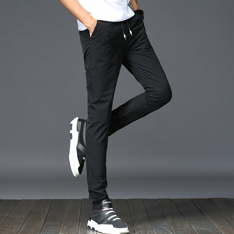 Mens Thick Stretch Trousers in Black on a model wearing a white T-shirt, showing the tapered legs with one knee raised