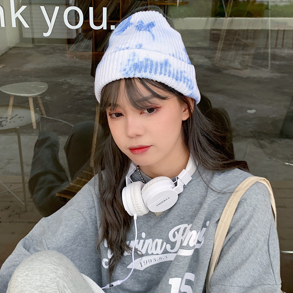 Unisex Tie Dye Beanie in blue and white on a woman wearing headphones, showing the ribbed knit and folded cuff