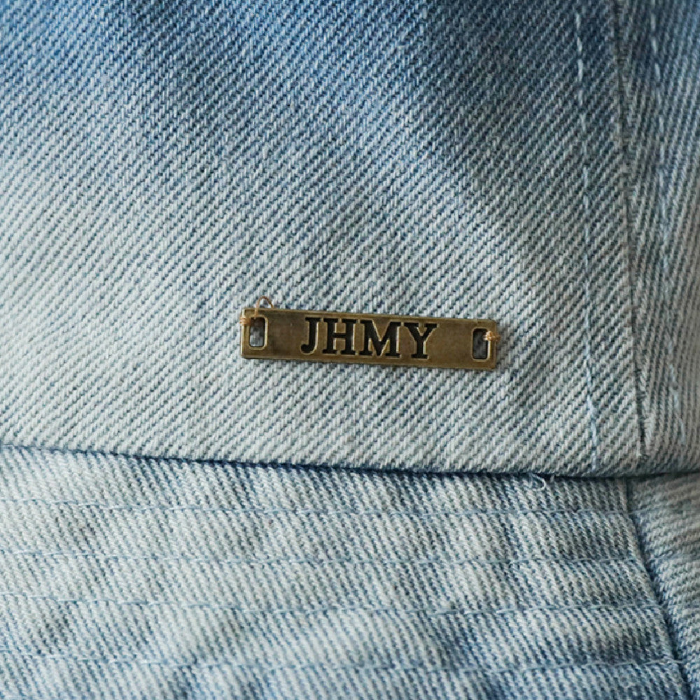 Vintage Washed Bucket Hat close-up showing light blue washed fabric, stitched brim and a small metal badge.