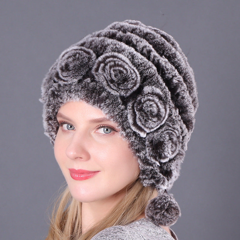 Womens Rabbit Fur Hat in grey with textured rows, matching floral details and hanging pom-poms.