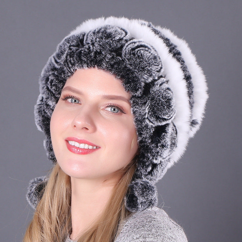 Womens Rabbit Fur Hat with white and grey rows, dark grey floral details and hanging pom-poms.