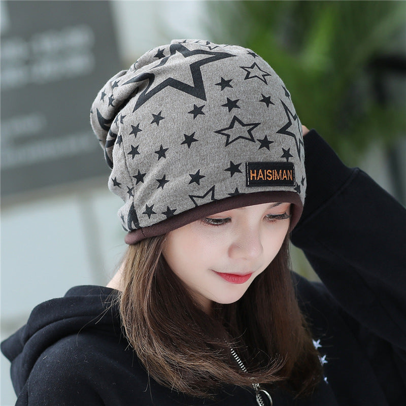 Womens Star Print Beanie in dark grey with black stars and a small front label, worn by a model looking down.