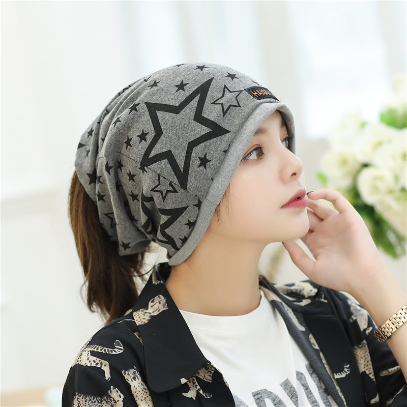 Womens Star Print Beanie in light grey with black outlined and solid stars, shown from the side on a model.