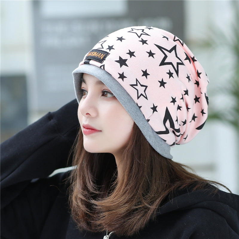 Womens Star Print Beanie in pink with black stars and a grey edge, worn by a model in a black hoodie.