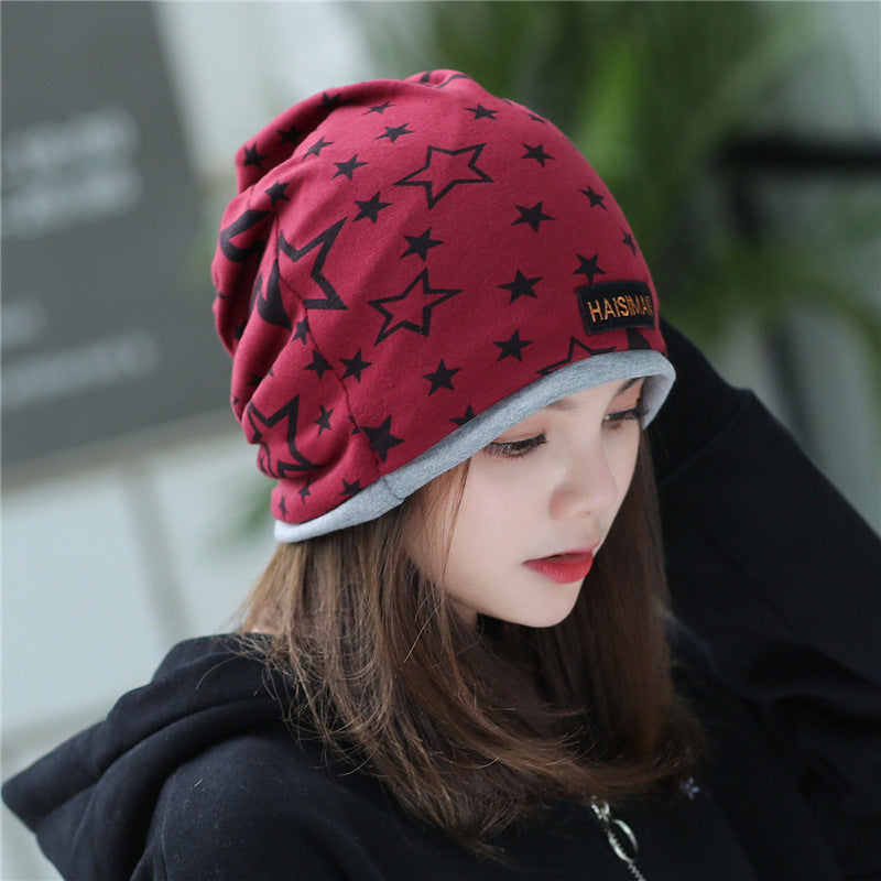 Womens Star Print Beanie in wine red with black stars and a grey edge, worn by a model looking down.